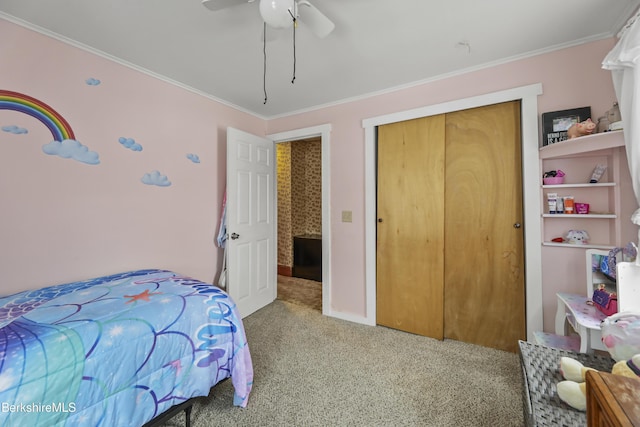 carpeted bedroom with a closet, ceiling fan, and ornamental molding