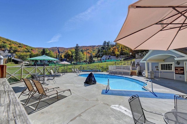 view of swimming pool with a mountain view and a patio area