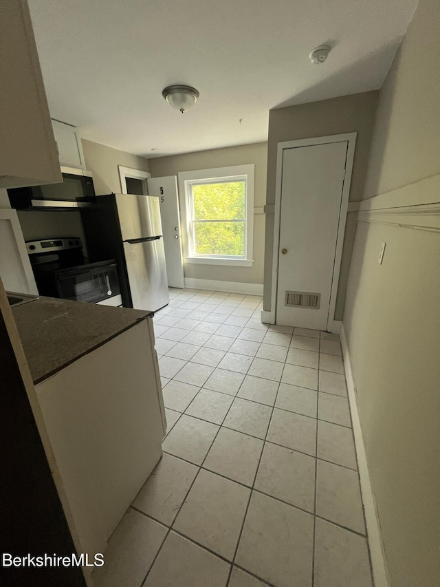 kitchen featuring stainless steel appliances, white cabinetry, and light tile patterned flooring