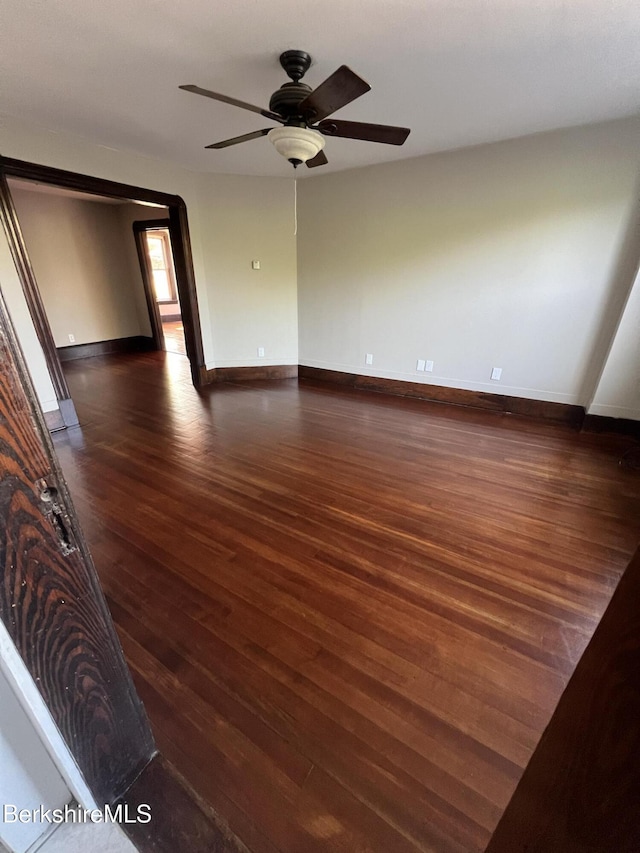 spare room with dark wood-type flooring and ceiling fan