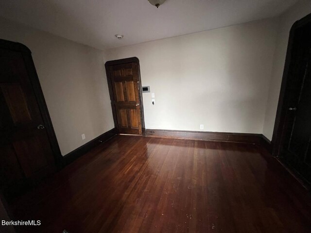 unfurnished room with dark wood-type flooring