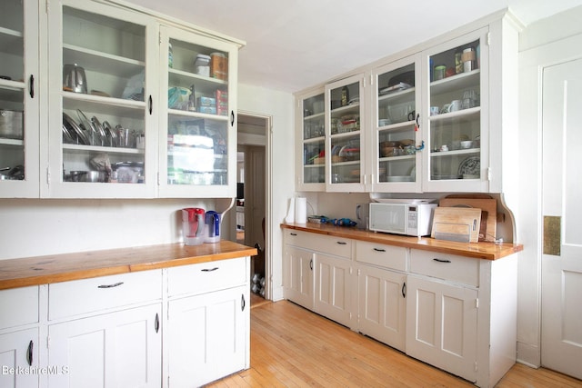 6-10 Manville St, Great Barrington, MA 01230 - kitchen with wooden counters, white microwave, glass insert cabinets, light wood finished floors, and white cabinets