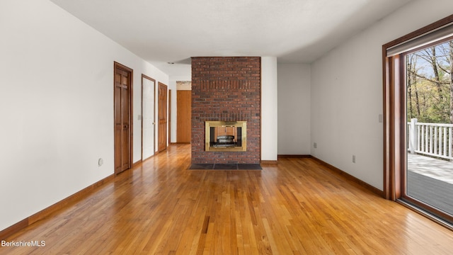 unfurnished living room featuring a fireplace, baseboards, and light wood-style floors
