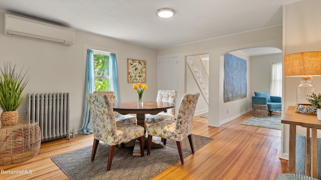 370 Park St, Great Barrington, MA 01236 - dining space with radiator heating unit, an AC wall unit, arched walkways, and light wood-type flooring