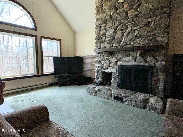 791 Partridge Rd, Lanesborough, MA 01237 - carpeted living room with a baseboard heating unit, a stone fireplace, and high vaulted ceiling