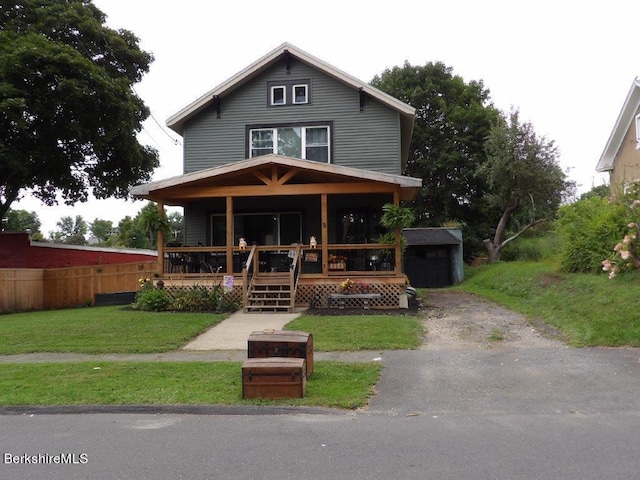 view of front of home featuring an outdoor structure, a porch, and a front yard