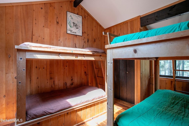 bedroom with wood finished floors, wooden walls, and lofted ceiling