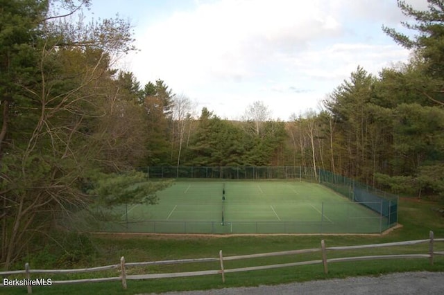 view of tennis court with a view of trees and fence