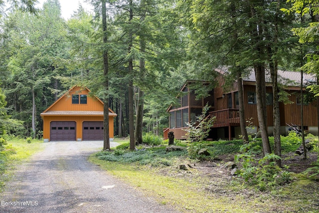 309 Tamarack Trl, Sandisfield, MA 01255 - view of front facade featuring a detached garage, a sunroom, an outdoor structure, and a forest view