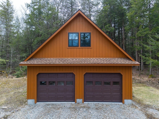 garage with driveway, a garage, and a forest view