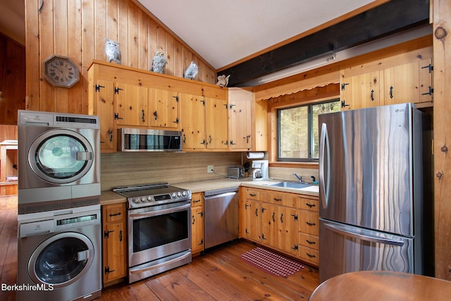 kitchen with tasteful backsplash, stainless steel appliances, light countertops, a sink, and stacked washing maching and dryer