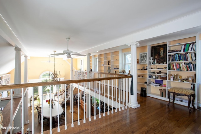 hall with hardwood / wood-style flooring, decorative columns, and a notable chandelier