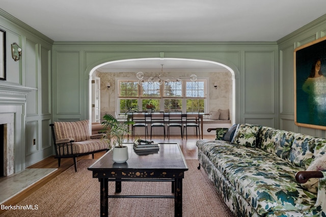 1030 W St, Pittsfield, MA 01201 - living area featuring a decorative wall, a chandelier, arched walkways, light wood-style flooring, and ornamental molding