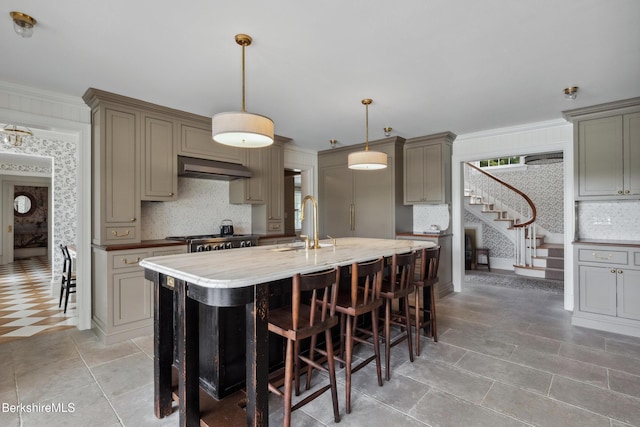 1030 W St, Pittsfield, MA 01201 - kitchen with backsplash, wall chimney range hood, an island with sink, a breakfast bar, and decorative light fixtures