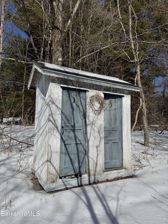 snow covered structure featuring a shed and an outdoor structure