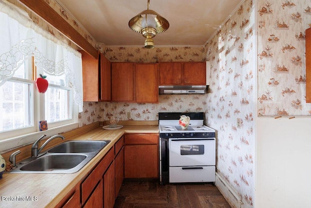 kitchen featuring white range with electric stovetop, light countertops, a sink, under cabinet range hood, and wallpapered walls