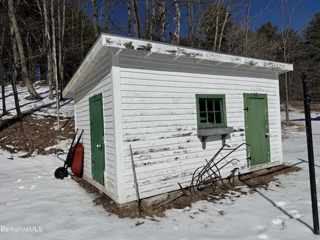 snow covered structure featuring an outbuilding