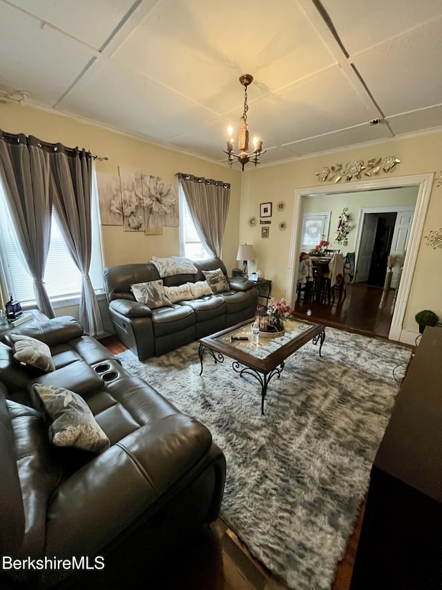 living room featuring ornamental molding, an inviting chandelier, and wood finished floors