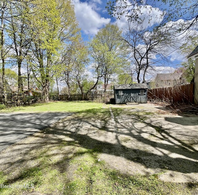 view of yard with an outbuilding, a storage shed, and fence