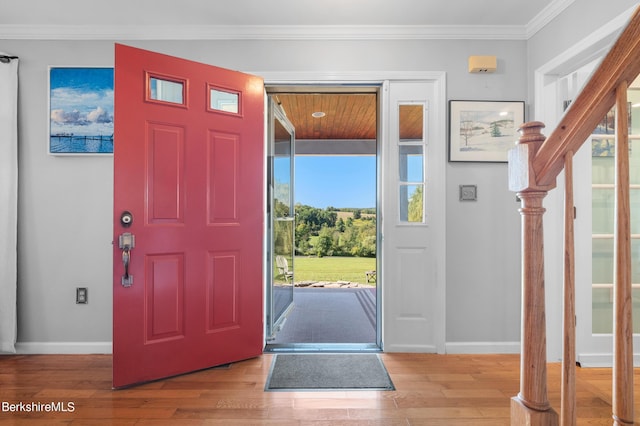 foyer featuring ornamental molding, light hardwood / wood-style flooring, and a healthy amount of sunlight