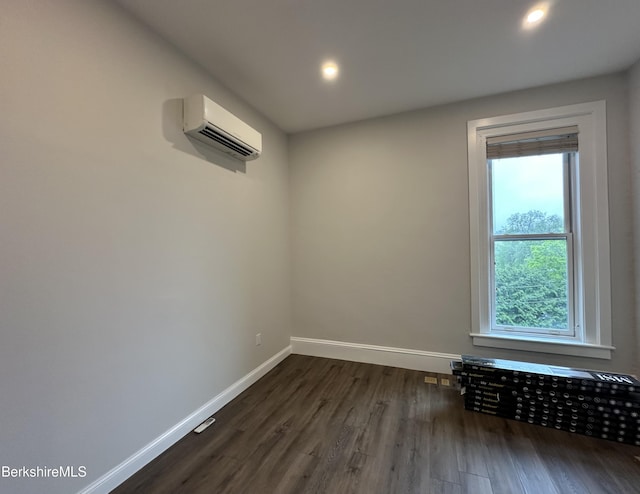 empty room featuring a wall mounted air conditioner, baseboards, dark wood finished floors, and recessed lighting