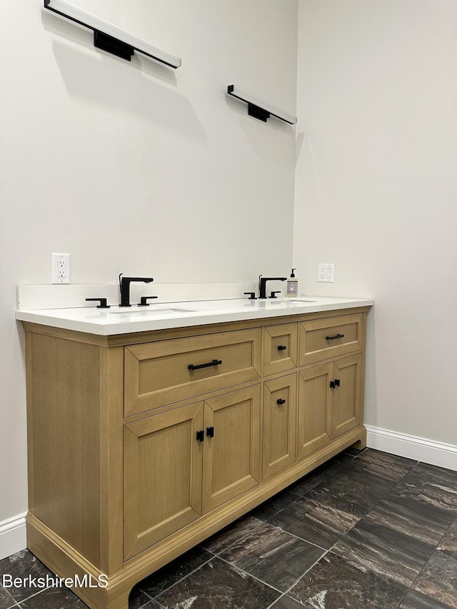 full bathroom with baseboards and double vanity