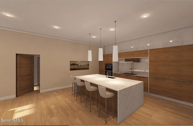 kitchen featuring light wood-type flooring, a breakfast bar, sink, a large island with sink, and pendant lighting