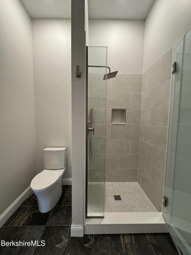 full bathroom with a shower stall, baseboards, and toilet