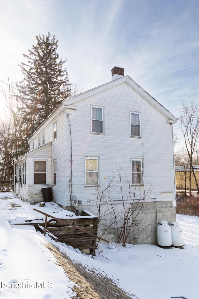 snow covered property featuring a chimney