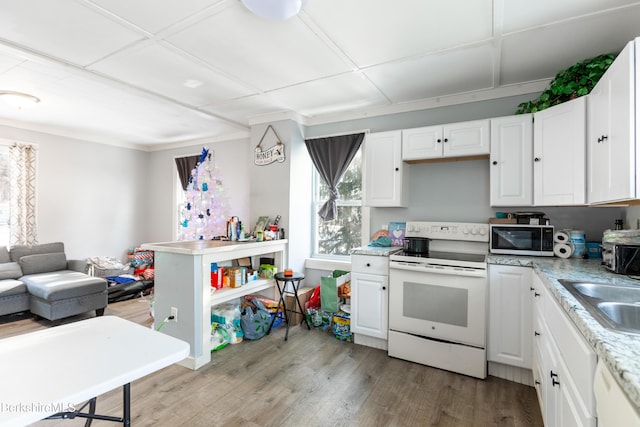 kitchen featuring open floor plan, white appliances, light wood-style flooring, white cabinetry, and a sink