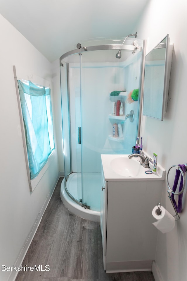bathroom featuring a shower stall, wood finished floors, vanity, and baseboards