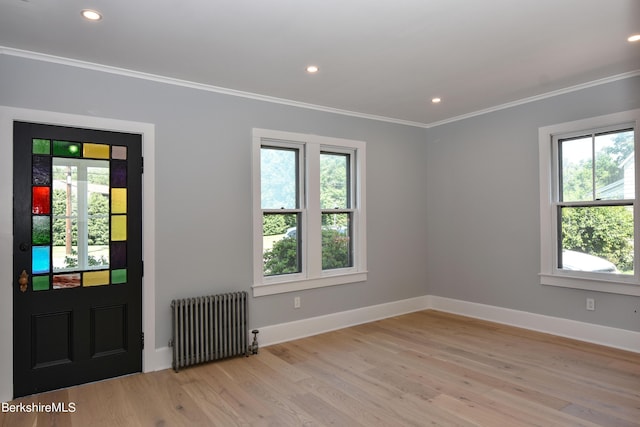 foyer entrance with ornamental molding, light hardwood / wood-style floors, and radiator heating unit