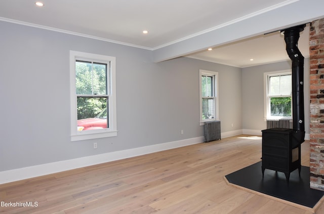 living room featuring radiator, a wood stove, crown molding, and light hardwood / wood-style flooring