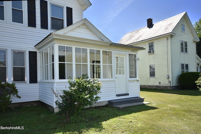 back of property with a yard and a sunroom