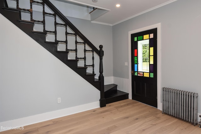 entrance foyer with ornamental molding, radiator, and light hardwood / wood-style flooring