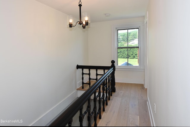 stairs featuring hardwood / wood-style floors and a notable chandelier