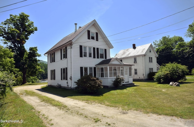 view of front of house with a front lawn and a sunroom