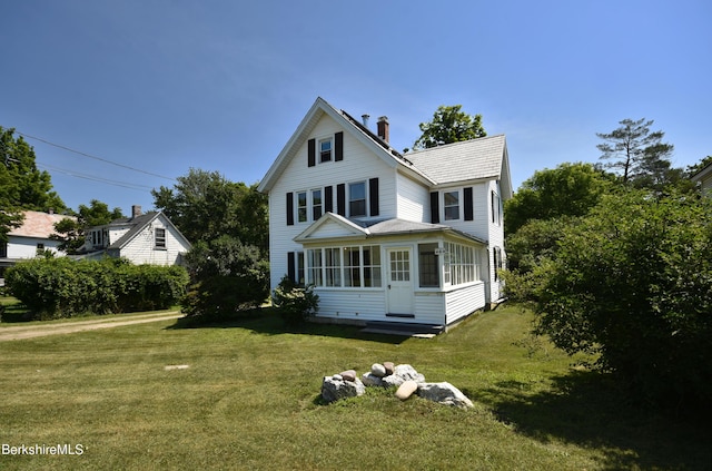 view of front facade featuring a front yard and a sunroom