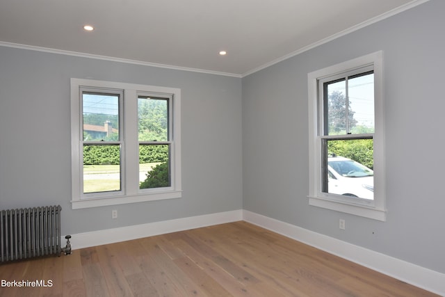 spare room with hardwood / wood-style floors, crown molding, radiator, and plenty of natural light