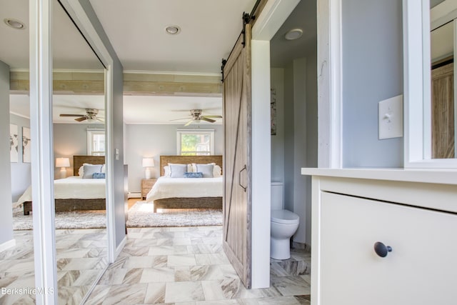 bedroom featuring a barn door, ensuite bath, baseboard heating, and ceiling fan