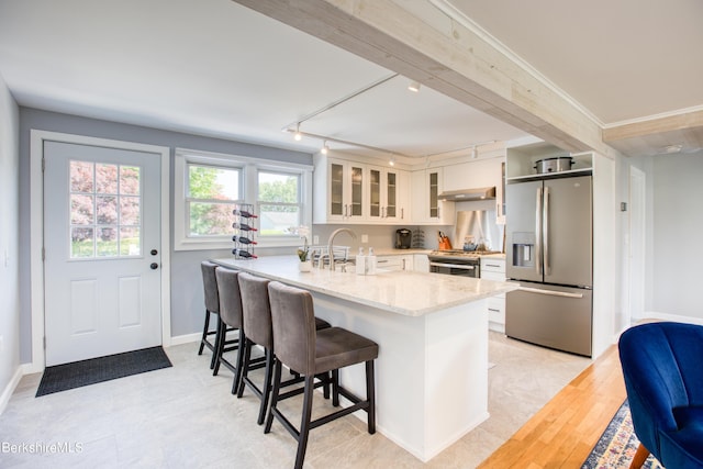 kitchen with white cabinetry, kitchen peninsula, light stone counters, and stainless steel appliances