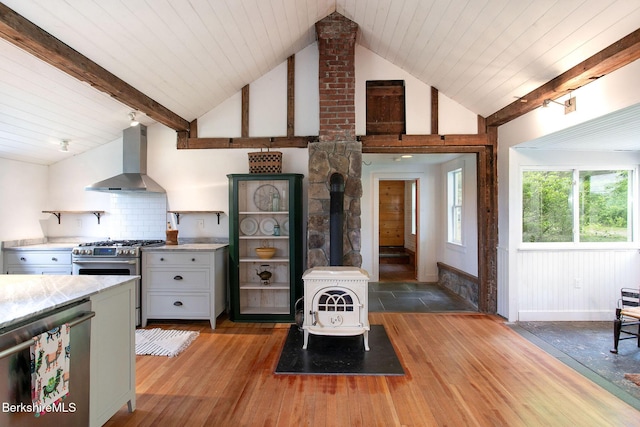 649 Hewins St, Sheffield, MA 01257 - kitchen with wall chimney exhaust hood, stainless steel appliances, a wood stove, light wood-style floors, and light countertops