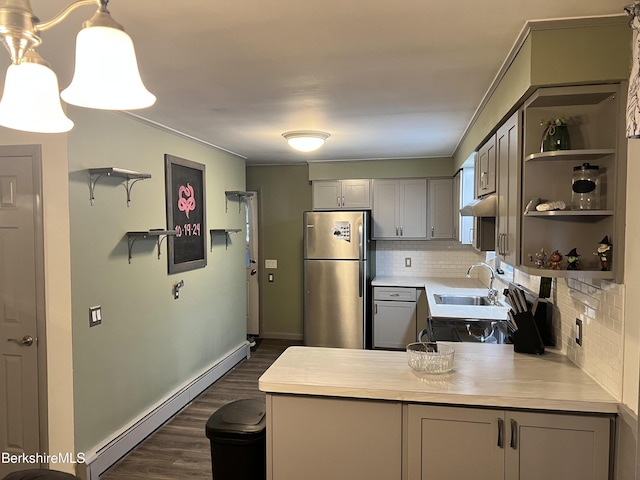 kitchen featuring decorative light fixtures, a baseboard heating unit, sink, gray cabinetry, and stainless steel fridge