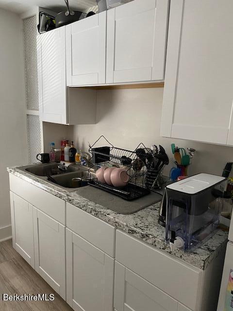 99 Meadow St, North Adams, MA 01247 - kitchen with white cabinets, light stone countertops, light wood-style floors, and a sink