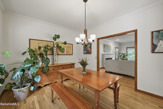 67 Dunmore Ct, Lenox, MA 01240 - dining area featuring light wood-style floors, crown molding, a chandelier, and a fireplace