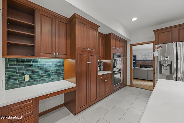 67 Dunmore Ct, Lenox, MA 01240 - kitchen with stainless steel fridge with ice dispenser, built in desk, open shelves, light countertops, and decorative backsplash