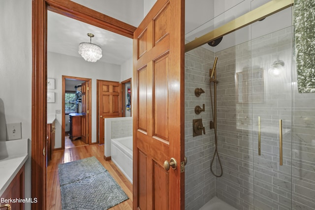 67 Dunmore Ct, Lenox, MA 01240 - full bath with wood finished floors, vanity, a bath, a tile shower, and a chandelier