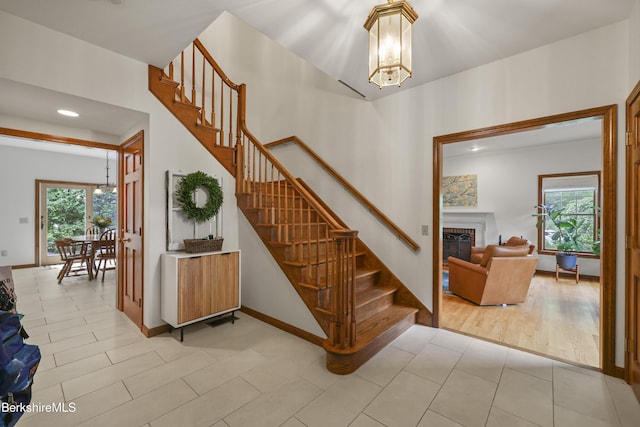 67 Dunmore Ct, Lenox, MA 01240 - stairway featuring a chandelier, healthy amount of natural light, a glass covered fireplace, and recessed lighting