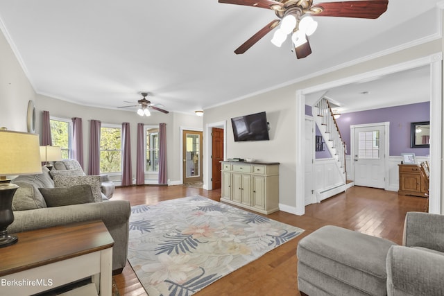 living room with ornamental molding, dark wood-style flooring, a baseboard radiator, stairway, and a ceiling fan