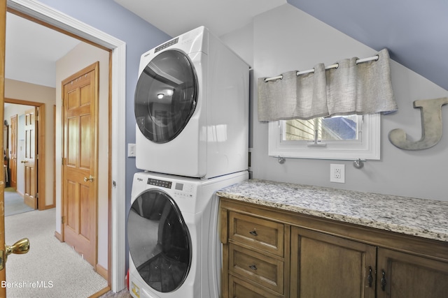 laundry room featuring cabinet space, light carpet, and stacked washer and clothes dryer